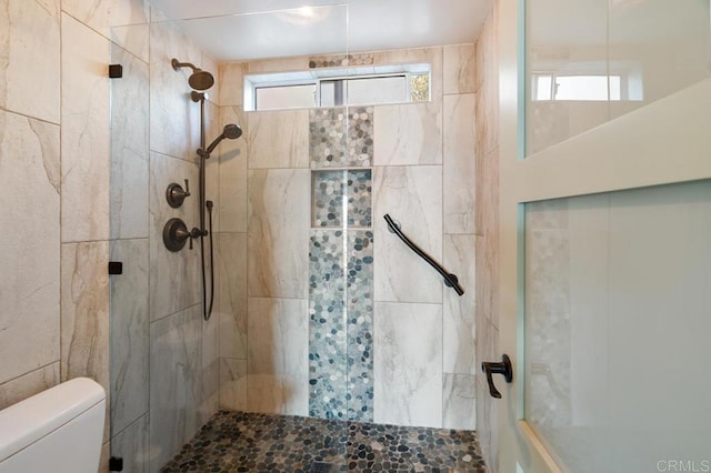 bathroom featuring a tile shower and toilet