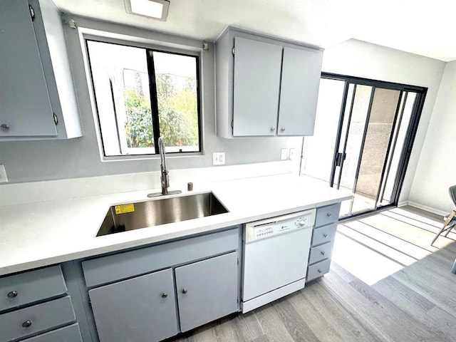 kitchen featuring white dishwasher, sink, gray cabinets, and light hardwood / wood-style floors