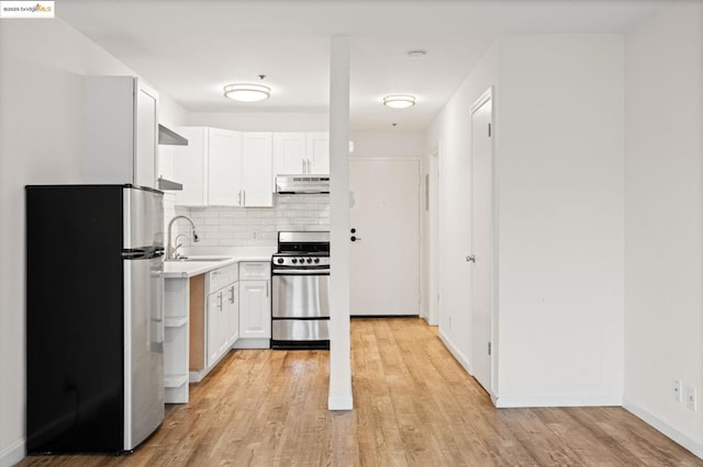 kitchen with white cabinetry, stainless steel appliances, tasteful backsplash, sink, and light hardwood / wood-style flooring