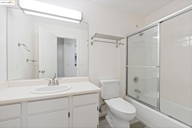 full bathroom featuring toilet, combined bath / shower with glass door, wood-type flooring, and vanity