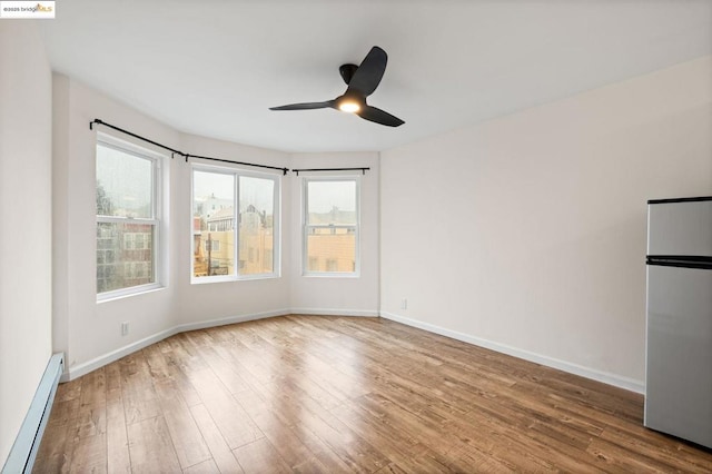 spare room featuring ceiling fan, a baseboard radiator, and hardwood / wood-style floors