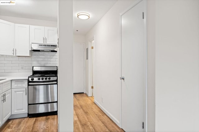 kitchen featuring decorative backsplash, stainless steel gas range, white cabinetry, and light hardwood / wood-style floors