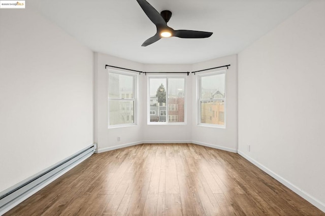 spare room with ceiling fan, a baseboard heating unit, and hardwood / wood-style floors