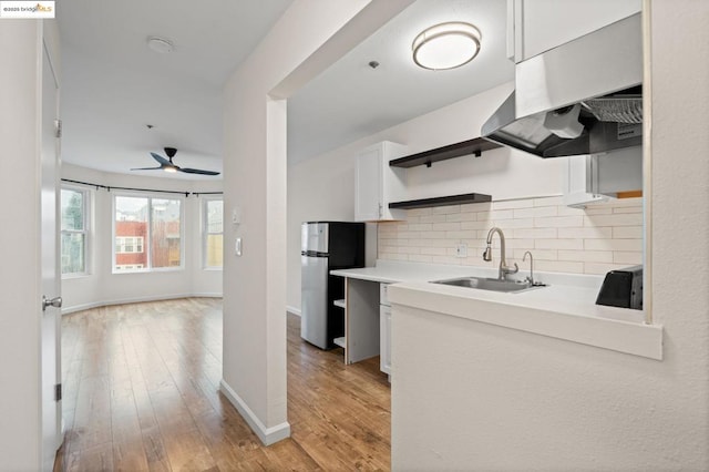 kitchen with white cabinetry, decorative backsplash, sink, stainless steel fridge, and light wood-type flooring