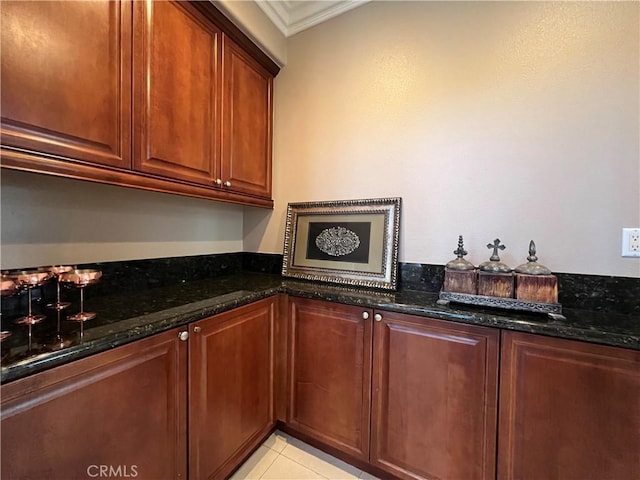 interior space featuring light tile patterned floors, ornamental molding, and dark stone countertops