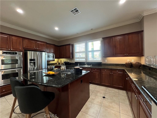 kitchen featuring appliances with stainless steel finishes, dark stone countertops, a breakfast bar, and sink