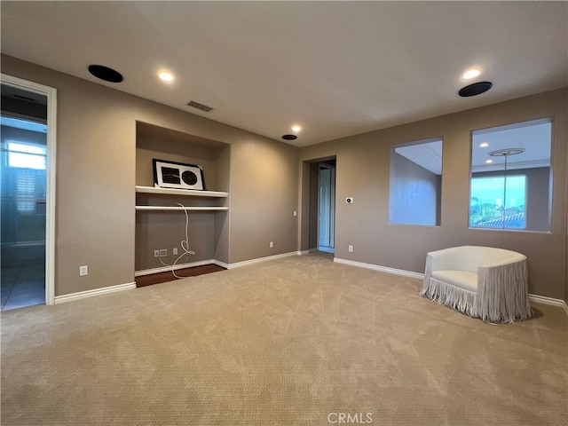 unfurnished living room with built in features, a healthy amount of sunlight, and light colored carpet