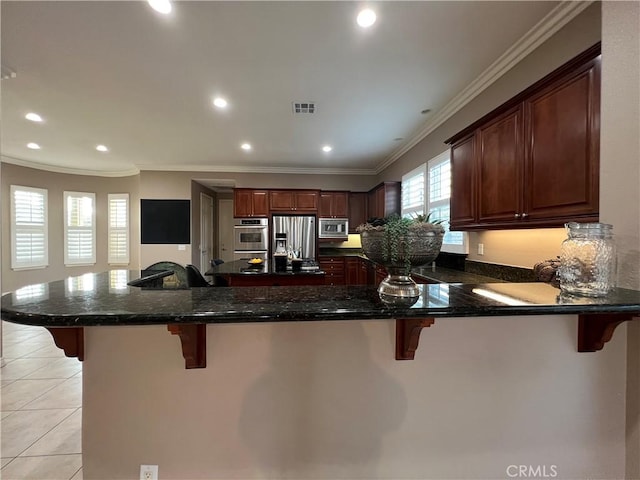 kitchen featuring stainless steel appliances, a kitchen bar, kitchen peninsula, and dark stone counters