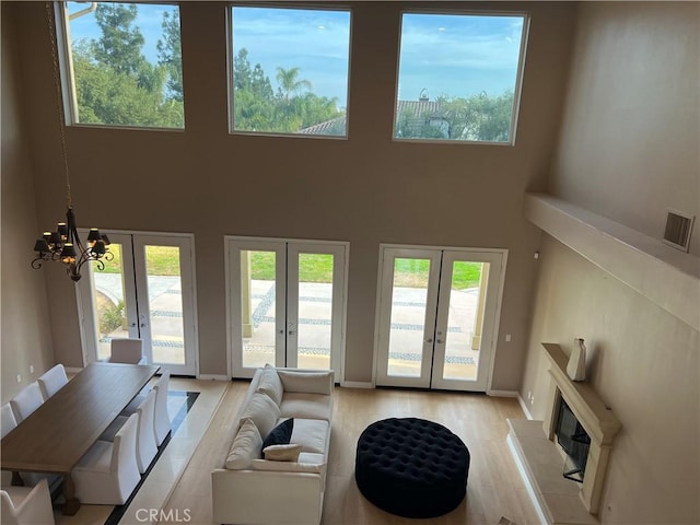 living room featuring french doors, an inviting chandelier, a wealth of natural light, and a high ceiling