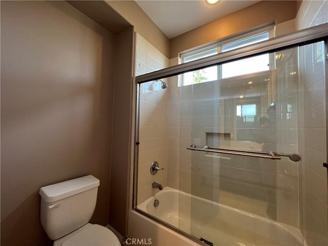 bathroom with shower / bath combination with glass door and toilet