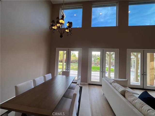 unfurnished living room featuring french doors, plenty of natural light, and an inviting chandelier