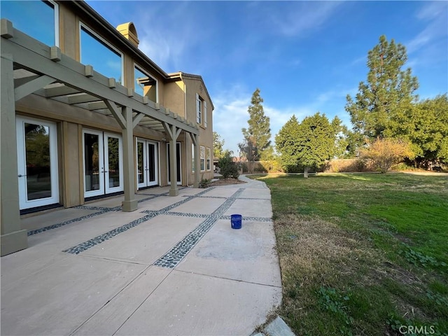 exterior space with a patio area, a lawn, french doors, and a pergola