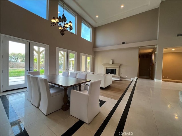 tiled dining space featuring a high ceiling, french doors, and a notable chandelier