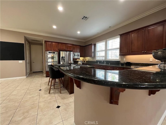 kitchen featuring sink, crown molding, light tile patterned flooring, appliances with stainless steel finishes, and a breakfast bar area