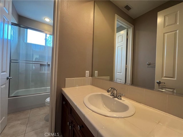 full bathroom featuring bath / shower combo with glass door, toilet, vanity, and tile patterned flooring