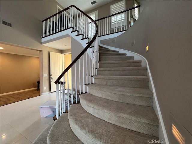 stairway featuring tile patterned floors and a towering ceiling