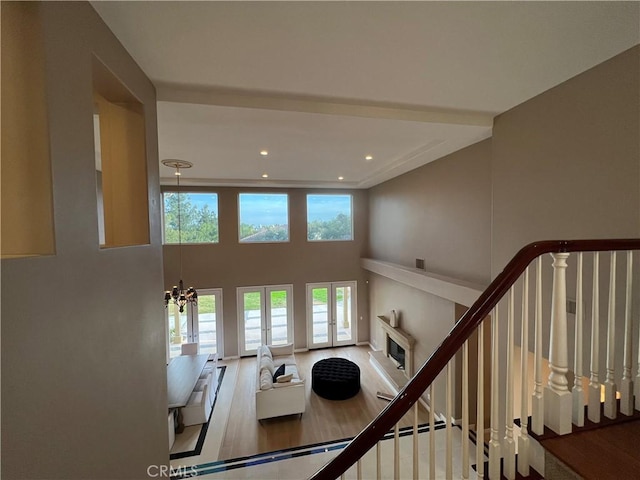 stairs with french doors, plenty of natural light, a high ceiling, and a chandelier