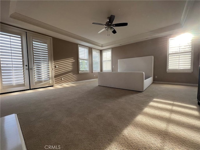 unfurnished living room with ceiling fan, french doors, a tray ceiling, and carpet flooring