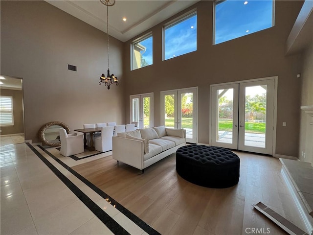 living room with a towering ceiling, french doors, and a notable chandelier