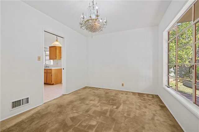 carpeted empty room with a chandelier and sink