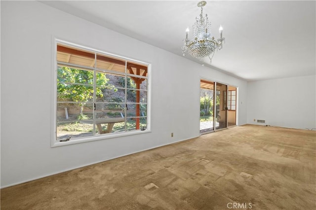 carpeted spare room with a notable chandelier and a healthy amount of sunlight