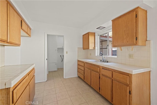 kitchen featuring light tile patterned floors, tile countertops, tasteful backsplash, and sink