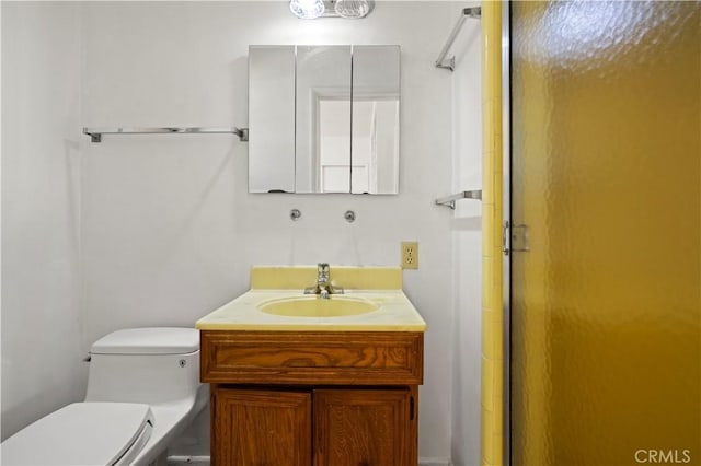 bathroom with toilet, vanity, and a shower with door