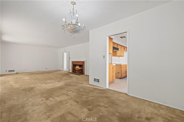 unfurnished living room featuring light carpet, a brick fireplace, and a chandelier