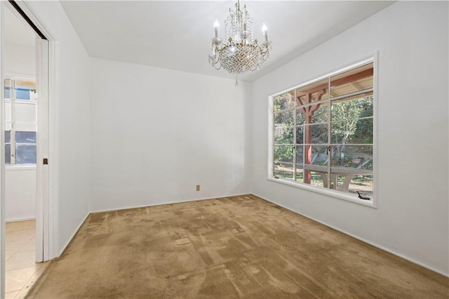 carpeted spare room with an inviting chandelier