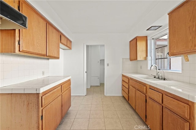 kitchen featuring sink, backsplash, light tile patterned floors, and tile counters