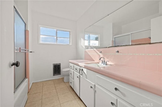 full bathroom with toilet, decorative backsplash, tile patterned floors, vanity, and shower / bath combination with glass door