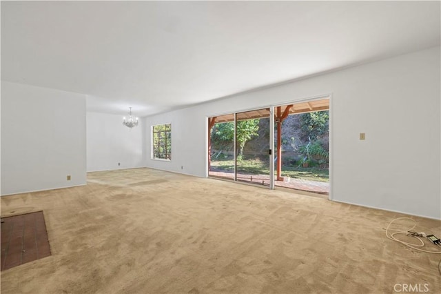 unfurnished living room with carpet floors, a healthy amount of sunlight, and a chandelier