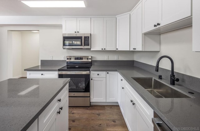 kitchen featuring sink, white cabinets, stainless steel appliances, and dark stone counters