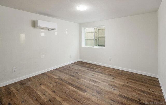 unfurnished room with an AC wall unit and dark hardwood / wood-style floors