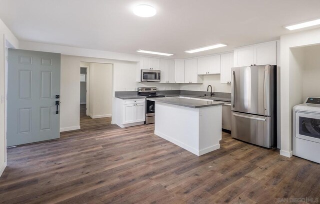 kitchen with white cabinetry, appliances with stainless steel finishes, washer / dryer, and a kitchen island