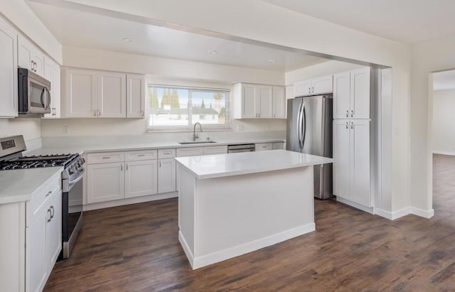 kitchen with appliances with stainless steel finishes, sink, white cabinetry, and a kitchen island