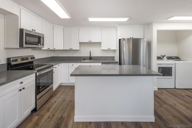 kitchen featuring a center island, sink, washing machine and clothes dryer, stainless steel appliances, and white cabinets