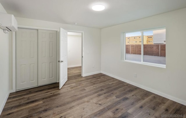 unfurnished bedroom with a closet, dark hardwood / wood-style flooring, and a wall mounted air conditioner