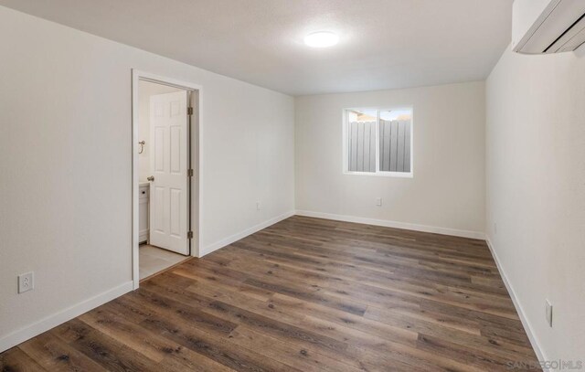 unfurnished room with dark hardwood / wood-style floors and a wall mounted AC