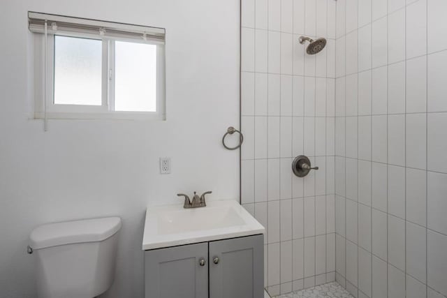 bathroom featuring toilet, tiled shower, and vanity