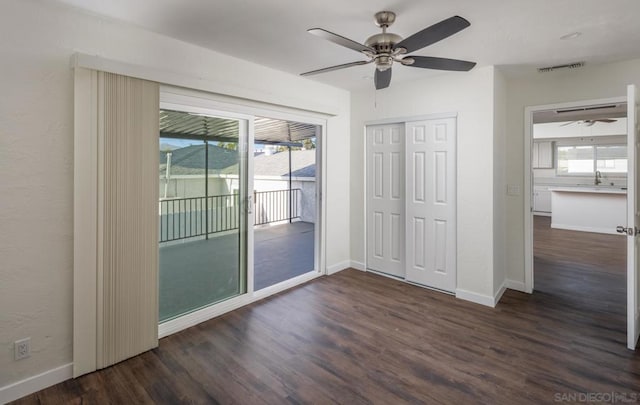 unfurnished bedroom featuring ceiling fan, dark hardwood / wood-style floors, access to outside, a closet, and sink