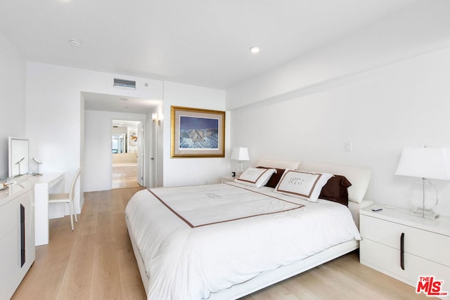 bedroom featuring light wood-type flooring and connected bathroom