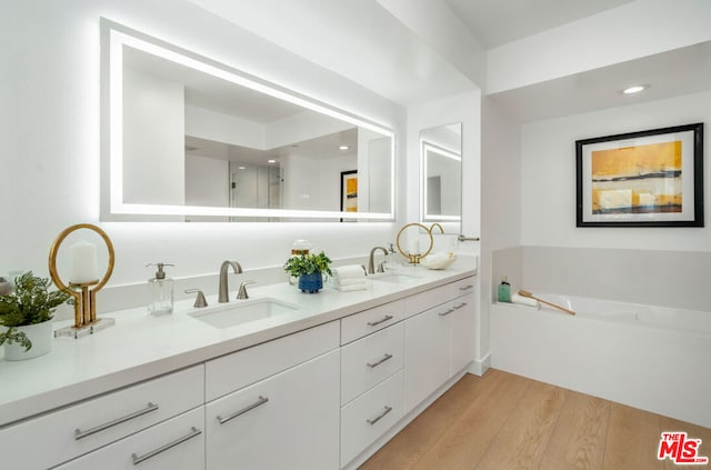 bathroom with hardwood / wood-style floors, vanity, and a bath