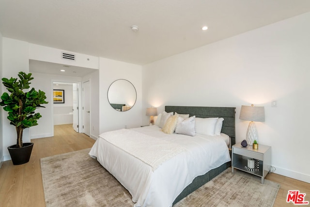 bedroom featuring ensuite bathroom and hardwood / wood-style floors