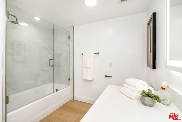 bathroom with hardwood / wood-style flooring and enclosed tub / shower combo