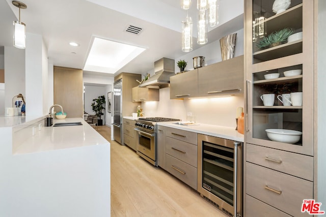 kitchen with beverage cooler, wall chimney exhaust hood, sink, gray cabinetry, and high quality appliances