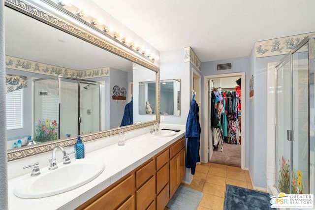 bathroom featuring tile patterned flooring, a shower with shower door, and vanity