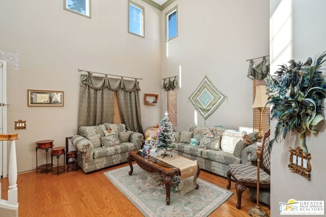 living room with decorative columns, a high ceiling, and light hardwood / wood-style floors