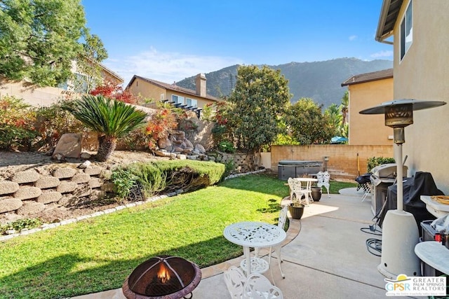 view of yard featuring a mountain view, a patio area, and an outdoor fire pit