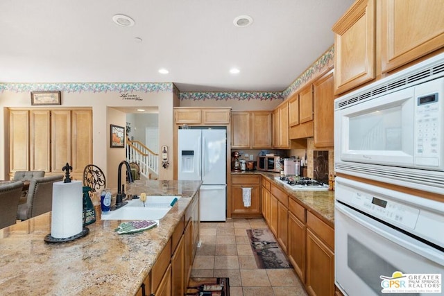 kitchen featuring light stone countertops, sink, and white appliances